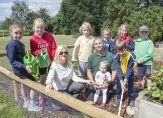 Members of the Llanbedr School Eco Group show off their garden to Clifford Jones Timber Director Sarah Jones Smith and Production Supervisor Michael Beaumont, a parent at the school, pictured with his daughter, Lilou, 18 months, Grace Meyman, 8, Beatrice Marston, 10, Harry Benjamin Williams, 8, Luciana Farinha, 9, Zoe Maddock, 8, Rhys Jones, 7, and Madoc Cotter, 7.